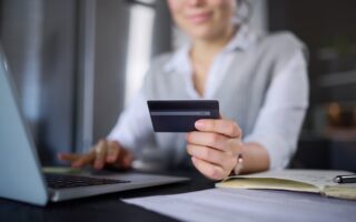 Kvinna vid laptop hållandes ett kreditkort