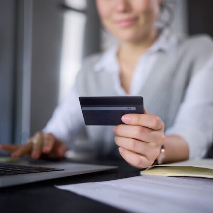 Kvinna vid laptop hållandes ett kreditkort